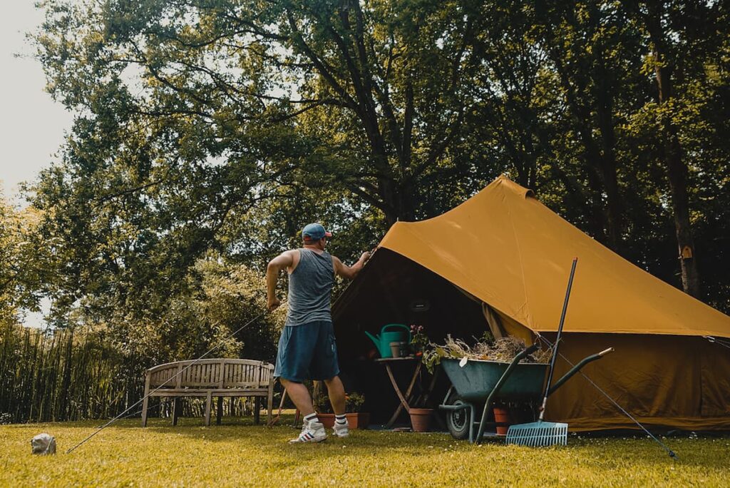 Autentic | Luxury Glamping Bell Tents - Someone tensioning the guyline of 5m yellow Autentic cotton canvas bell tent