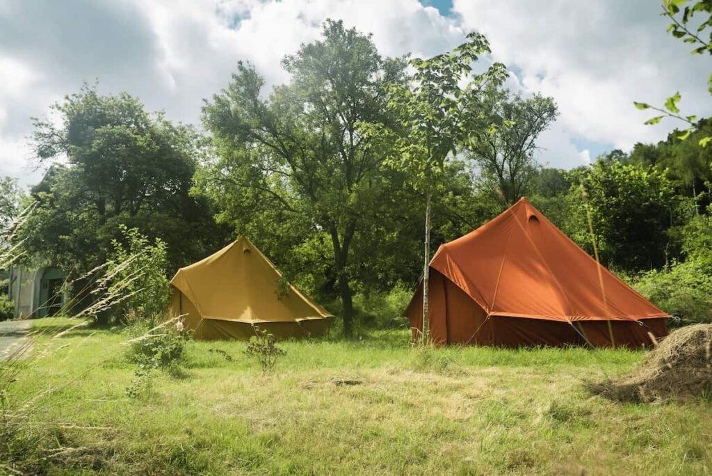 Autentic | Luxury Glamping Bell Tents - Orange and yellow 5m bell tents of Autentic in a grass field