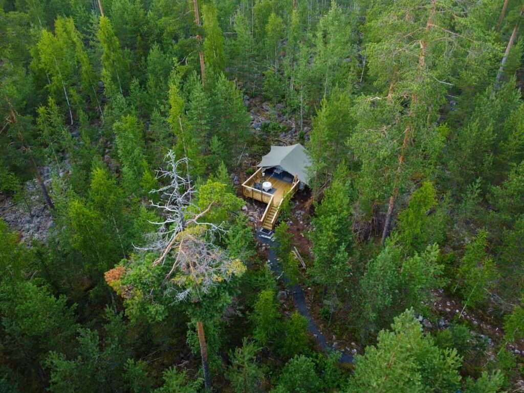Autentic | Luxury Glamping Bell Tents - Drone view of the Autentic Total Patrol Tent set up in the middle of the forest at the Hideaway glamping site in Finland